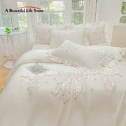 Cream-colored ice silk duvet set with embroidered ruffles featuring delicate bows and pink floral accents for bedroom bedding