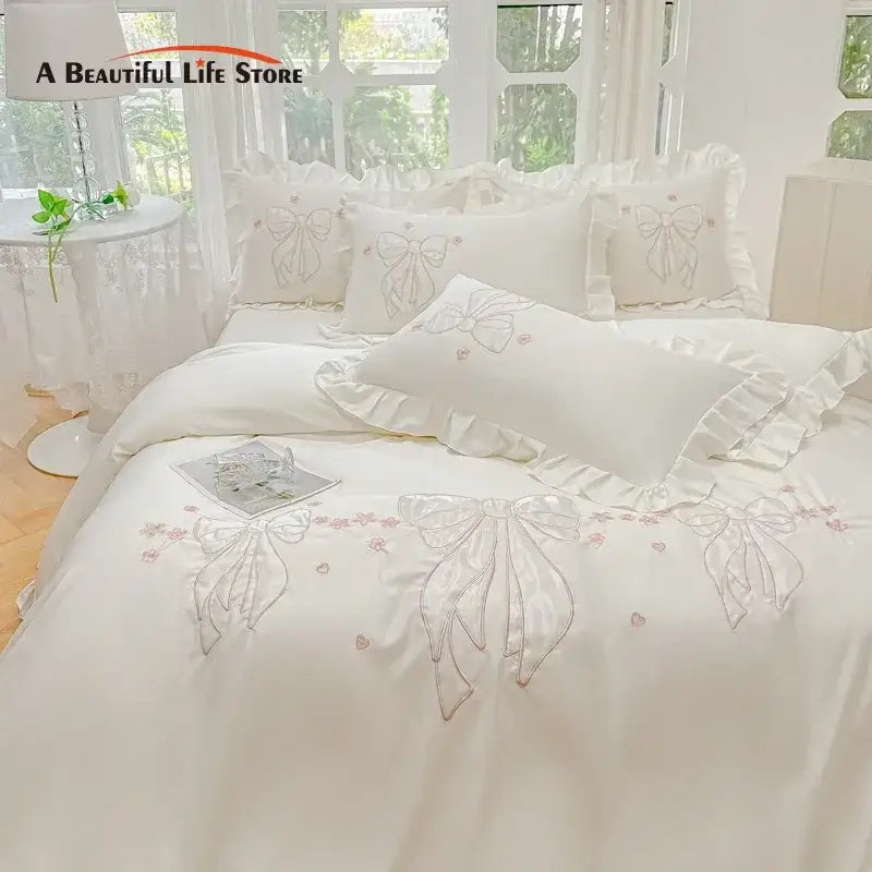 Cream-colored ice silk duvet set with embroidered ruffles featuring delicate bows and pink floral accents for bedroom bedding