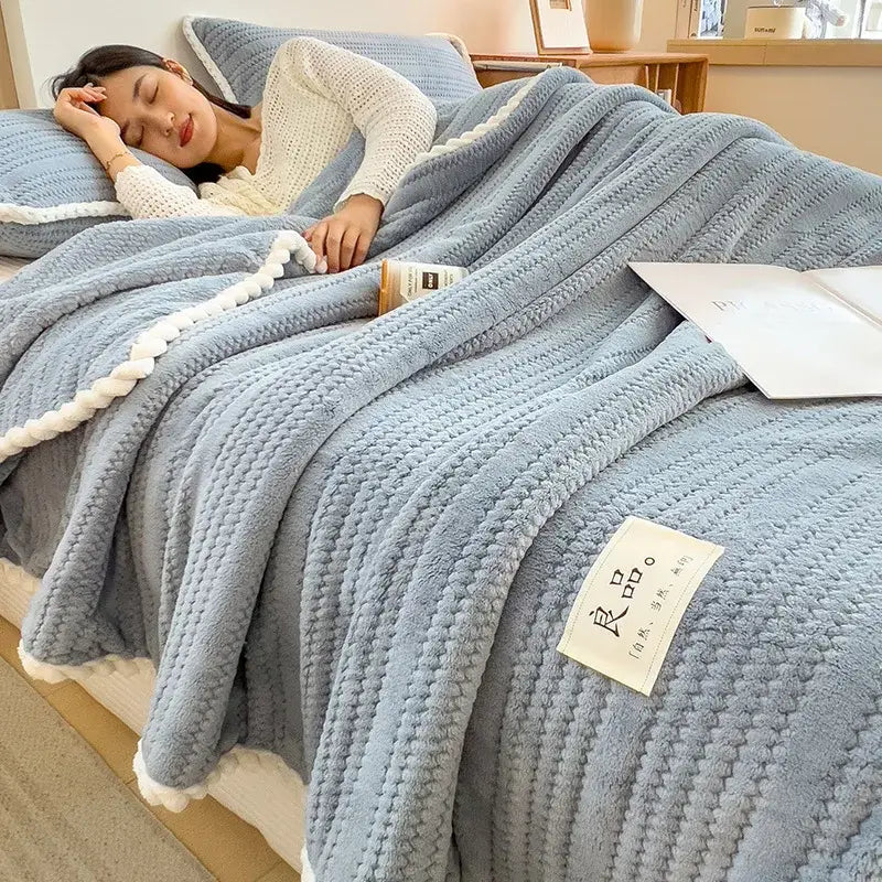 Soft light blue double sided jacquard milk velvet blanket with white pom-pom trim and plush textured fabric