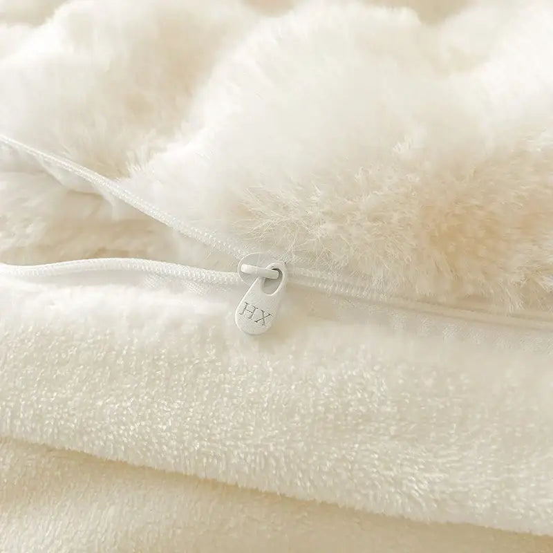 Cream plush rabbit fur bedding set showcasing a white faux fur pillow with matching zipper and pull tab detail