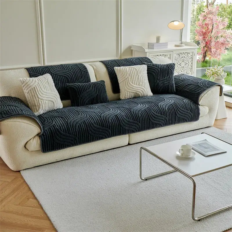 Dark navy blue quilted wave plush sofa cover draped over cream living room couch with textured cushion pattern