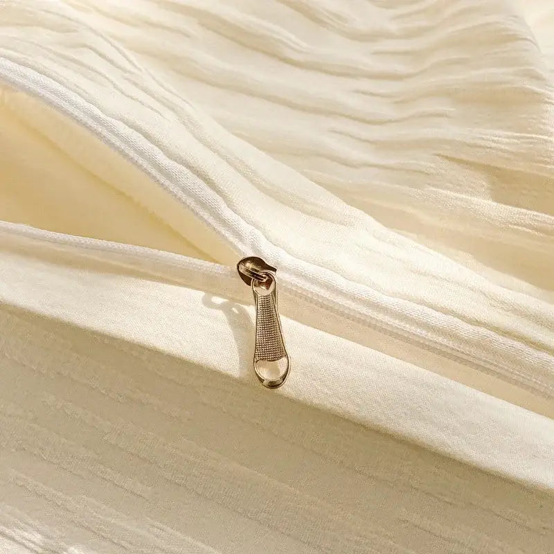 A gold-toned zipper pull on a cream ribbed bubble yarn duvet cover set made from soft textured fabric