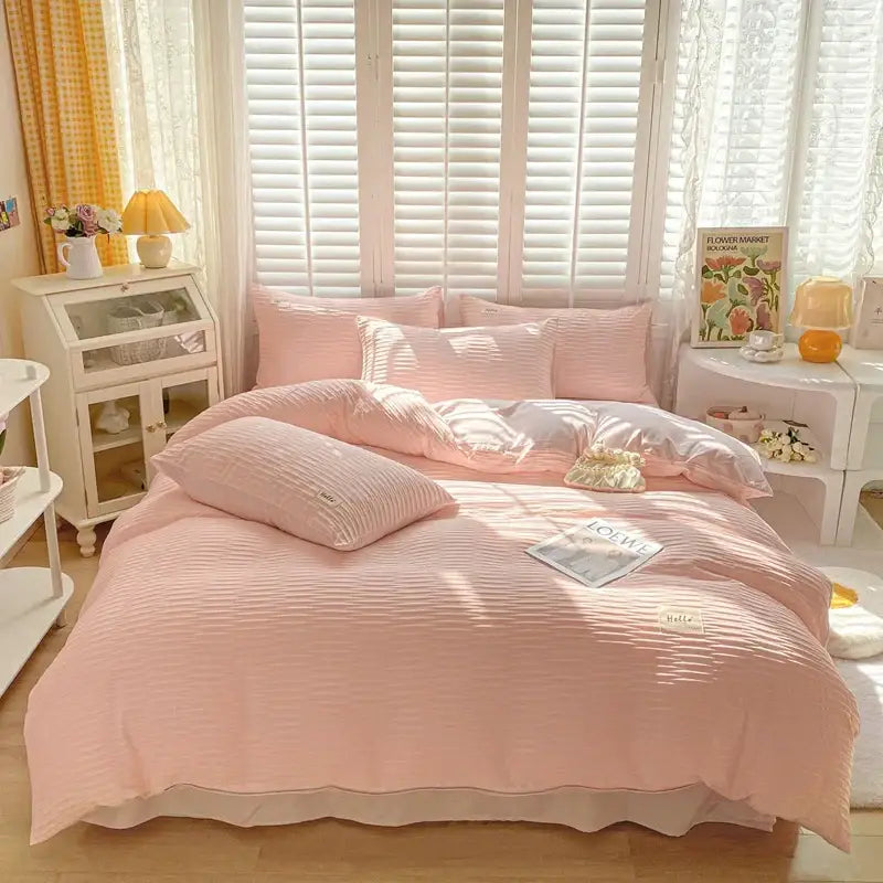 A soft pink ribbed cotton duvet cover set with matching pillows and a ruffled edge for bedroom bedding