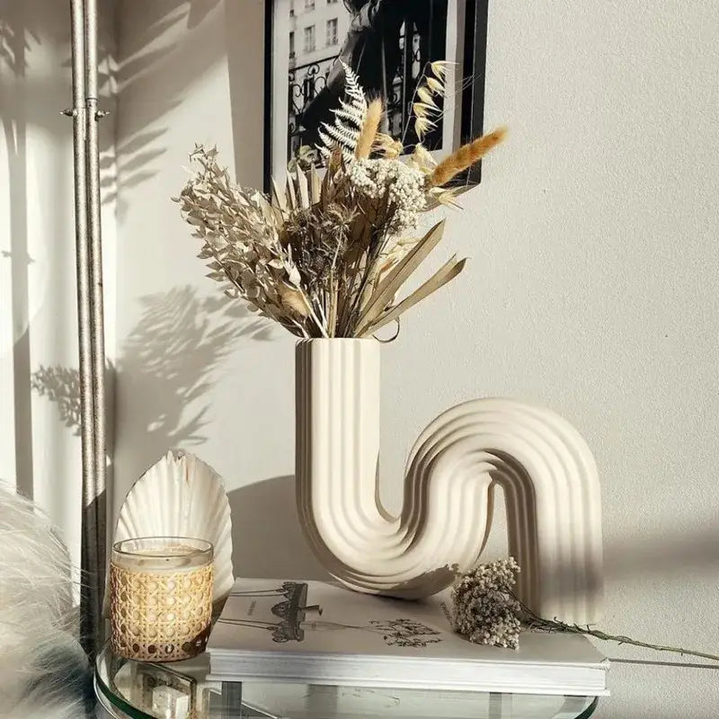 Cream ribbed geometric ceramic vase with a sleek curved design for living room decor by Decorbites geometric ceramic