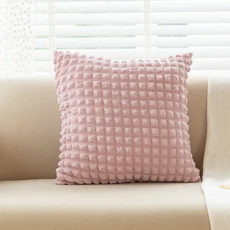 A soft pink elastic puff plaid cushion cover with raised grid texture on a beige couch for living room decor