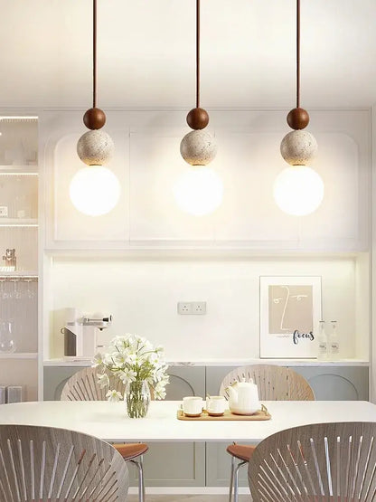Three cream style led pendant lamps with matte brown tops and textured concrete spheres on copper cords for decorbites bedroom decor