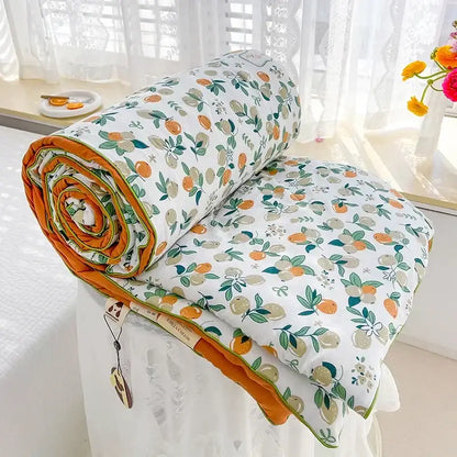 A cozy rolled-up cream teddy bear breathable double gauze quilt with citrus pattern and orange lining for bedroom decor