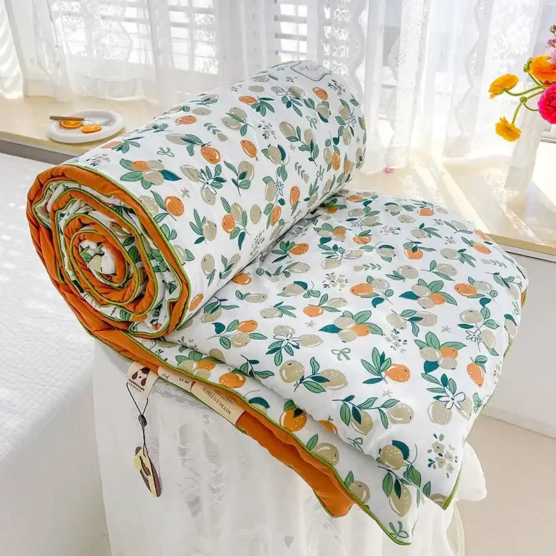 A cozy rolled-up cream teddy bear breathable double gauze quilt with citrus pattern and orange lining for bedroom decor