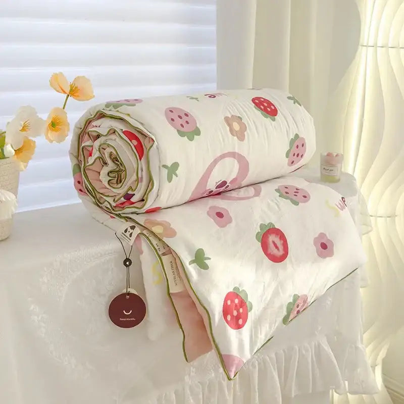Rolled-up cream teddy bear breathable double gauze quilt with strawberry floral pattern in pink red green beige accents