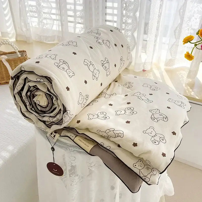 A cream teddy bear breathable double gauze quilt with black outlined bears and brown flowers, dark gray stitched edges