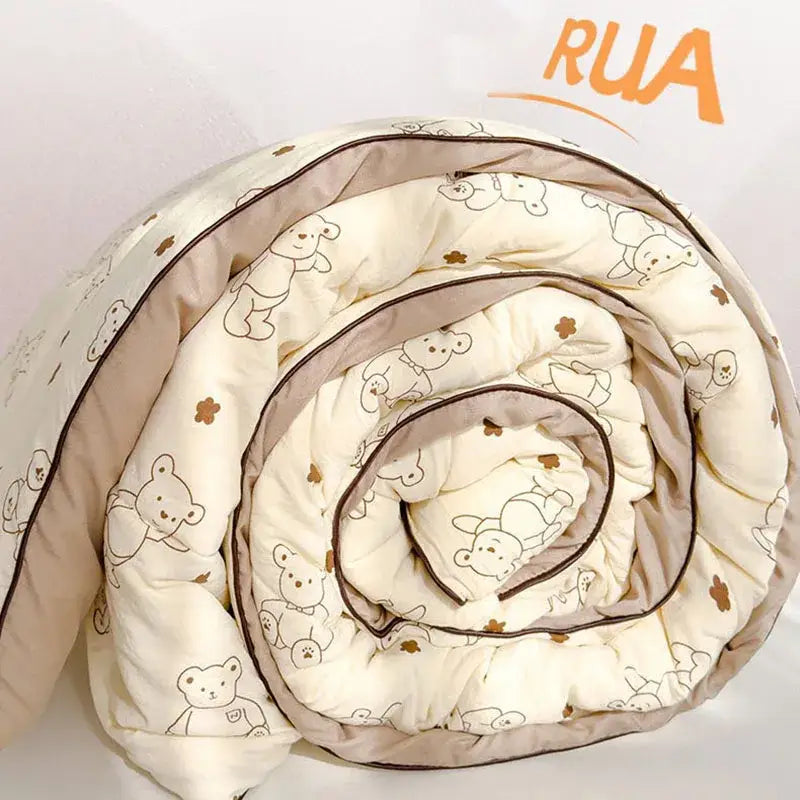 A cream teddy bear double layered soya fibre quilt rolled up featuring outlined bears and small brown flowers