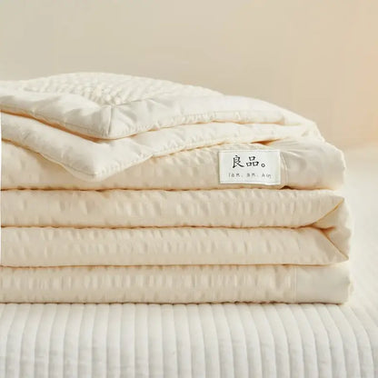 A neatly folded cream textured ice cream air bubble summer quilt with subtle pattern and chinese label by decorbites