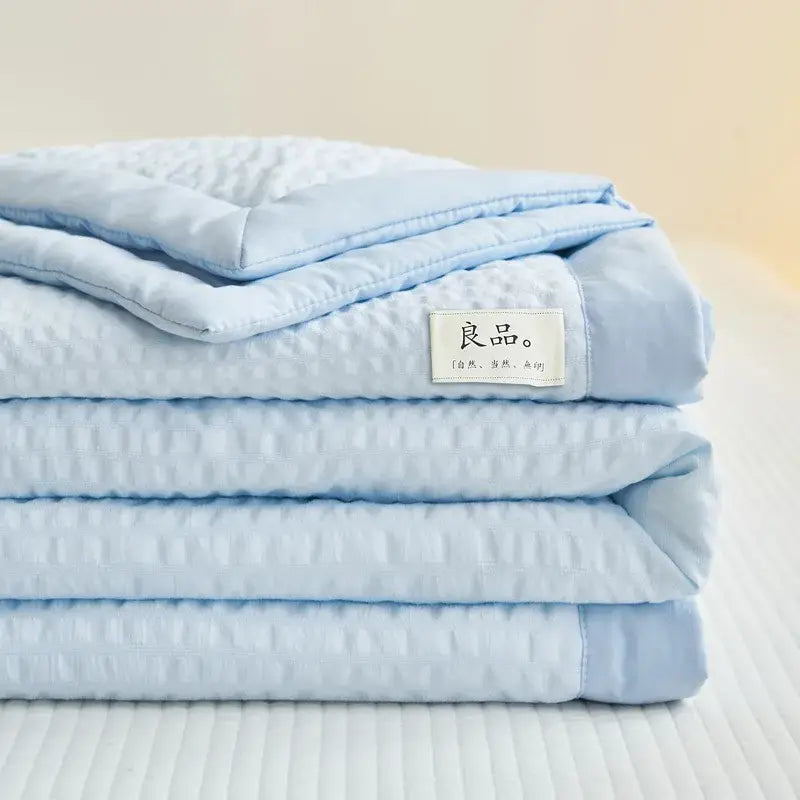 A soft light blue cream textured ice cream air bubble summer quilt with a subtle pattern and neatly folded edges