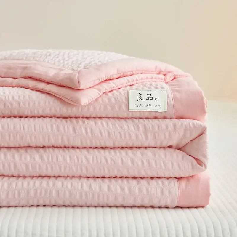 A soft pink decorbites ice cream air bubble summer quilt with subtle texture and a white label with chinese characters