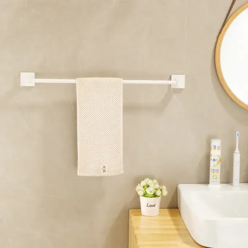 Cream white bathroom set featuring a textured towel hanging on a sleek wall-mounted towel rack with storage shelf