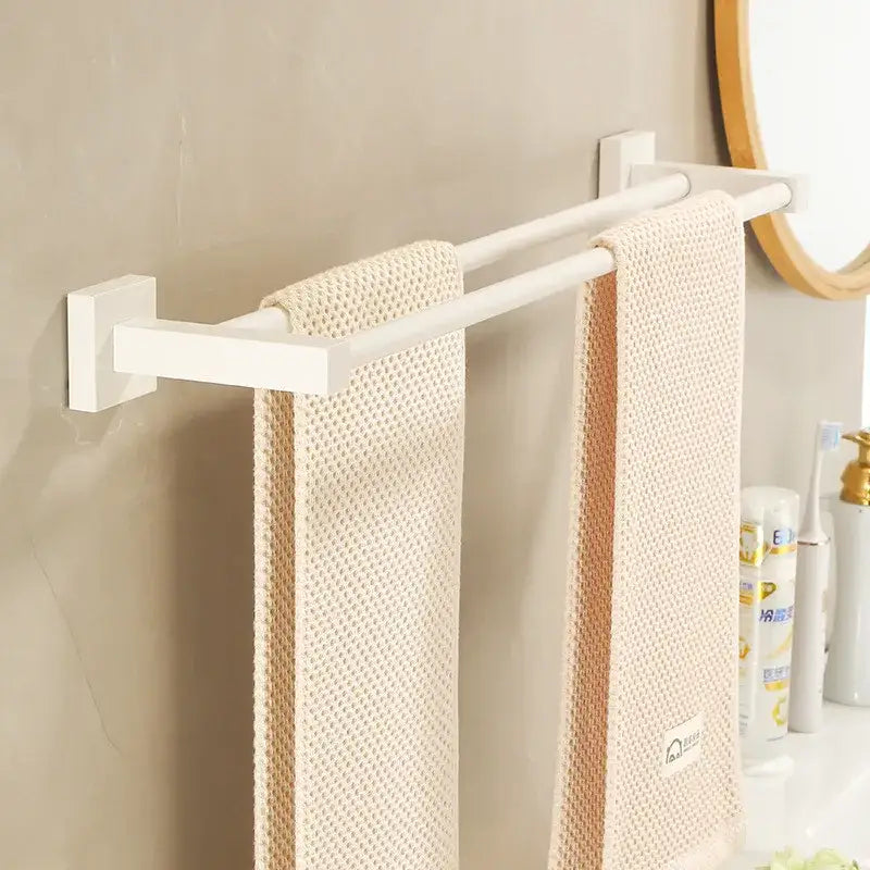 Cream white bathroom set with a white double-bar towel rack holding two beige textured towels for organized storage