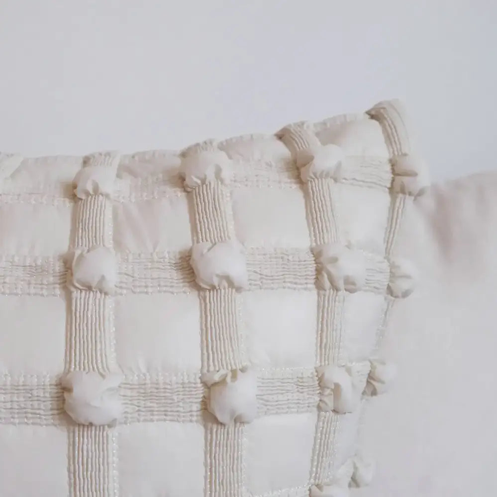 Off-white cream white plaid cushion cover with textured quilted squares and decorative pom-poms for living room decorbites decor