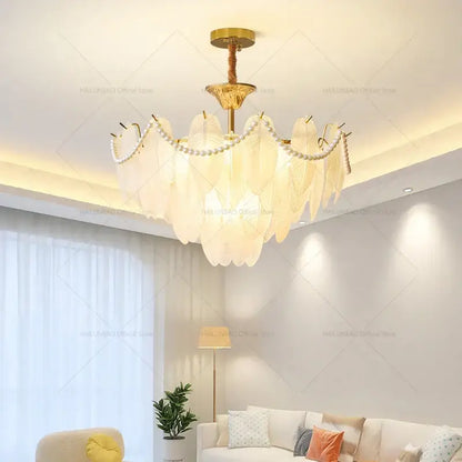 Elegant gold-toned decorbites cream wind chandelier with translucent white feather shades and pearl accents for living room light