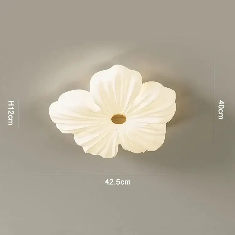 A delicate white ceramic flower-shaped ceiling light with a soft glowing center from decorbites cream wind eye collection