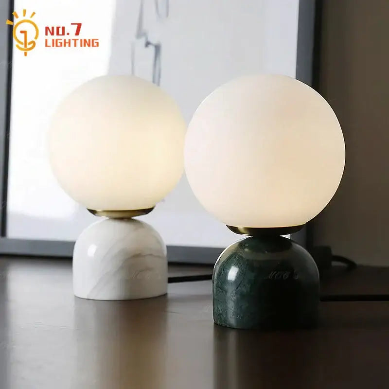 Two spherical glass table lamps with cream wind marble bases in white and dark green for elegant decorbites cream wind lighting