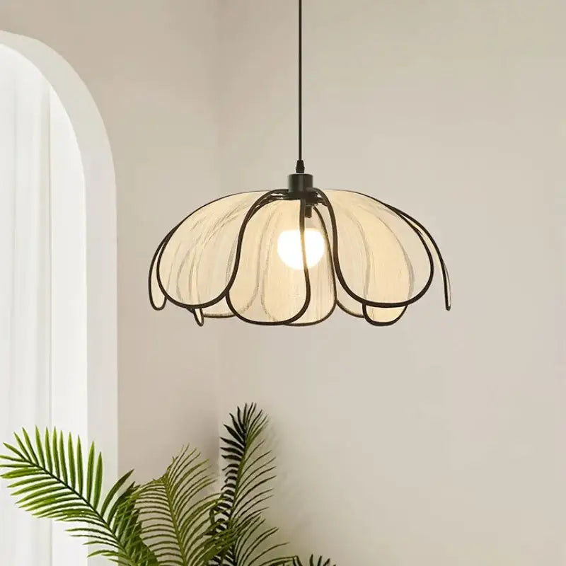 Cream-colored pendant light with black metal frame and translucent petals made of creamy abaca fabric for dining room decorbites