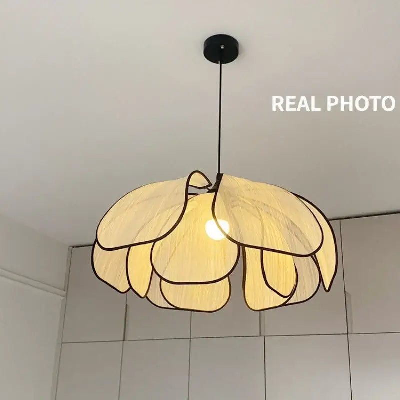 A warm-toned pendant light with layered petal shapes made of creamy abaca fabric and dark woven outlines by decorbites