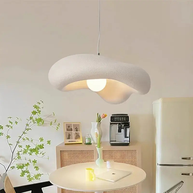Creamy style resin pendant light shaped like an off-white cloud with a textured surface and warm glow for dining room