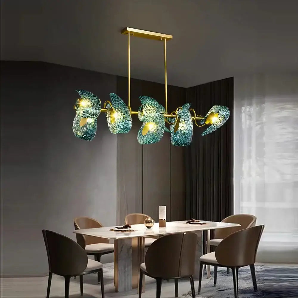 A modern pendant light with five translucent teal decorbites blue glass shades and gold-toned metal frame chandelier