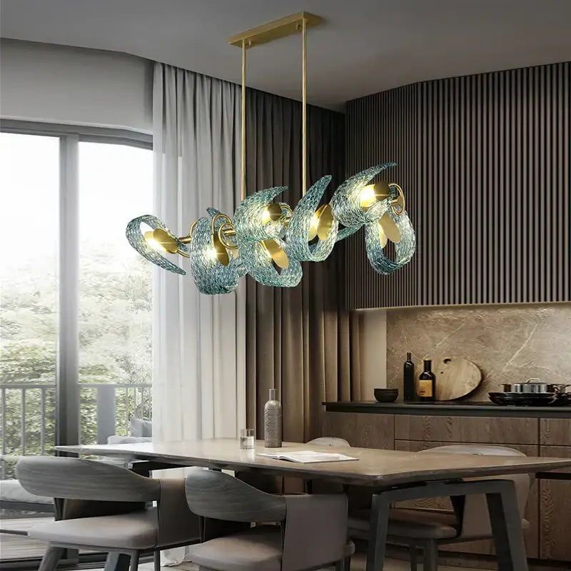 A modern pendant light with translucent teal decorbites blue glass shades and gold-toned metal accents for luxury decor