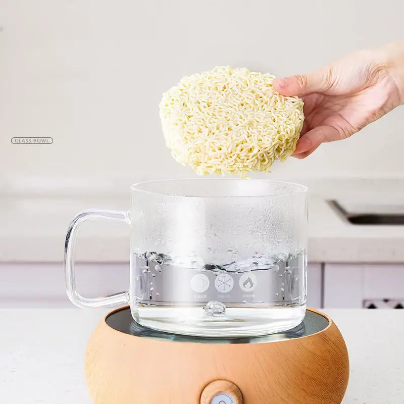 A clear glass salad bowl with handle filled with water on a wooden base heater for kitchen and dining room use