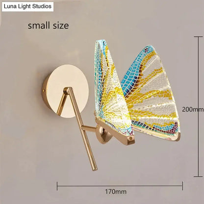 A creative colorful butterfly led wall lamp with gold finish and mosaic yellow blue and white glass wings for bedroom use