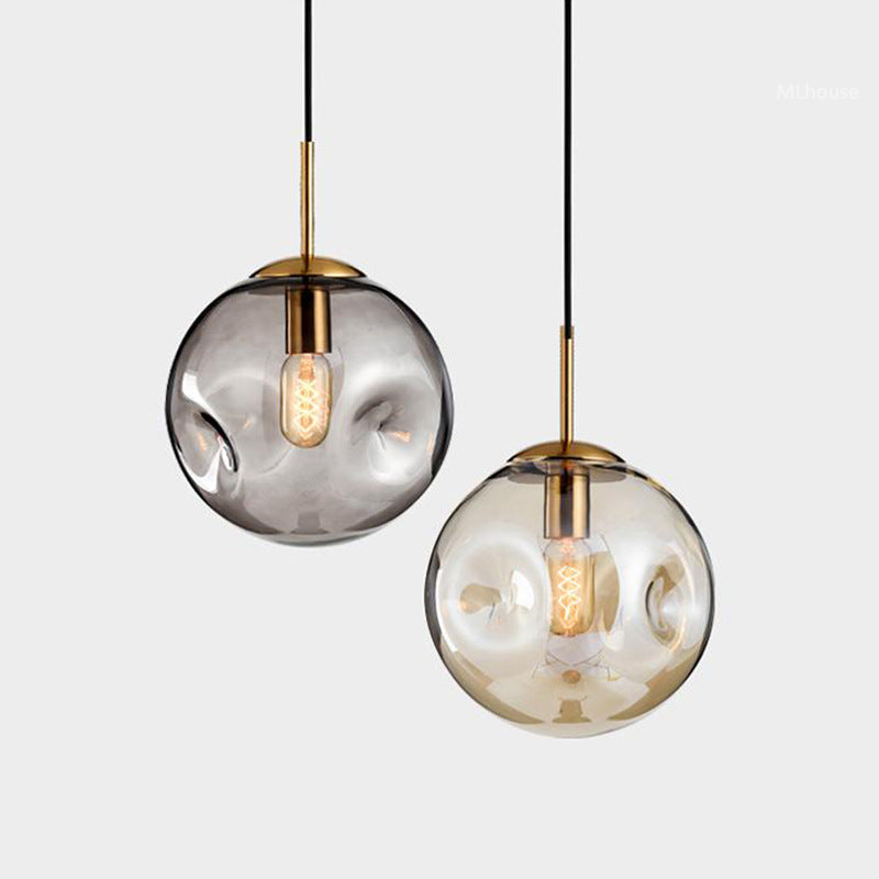 Modern glass globe pendant light with brass accents and black cord.