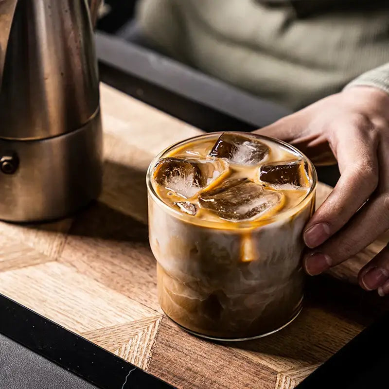A clear glass coffee smoothie cup with ice cubes on wooden surface by decorbites creative heat resistant drinkware
