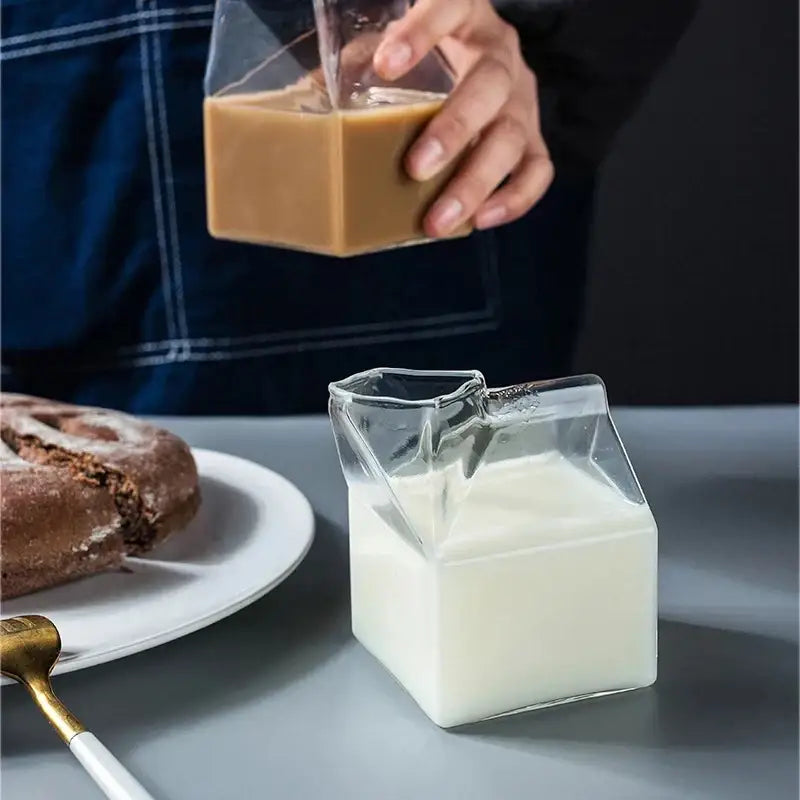 Clear glass milk box with spout filled with white liquid part of decorbites creative milk glass cup set of 2