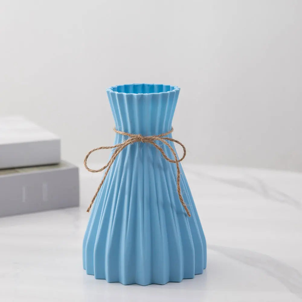 A light blue pleated plastic flower bottle type vase with twine bow in modern dry flower bottle design