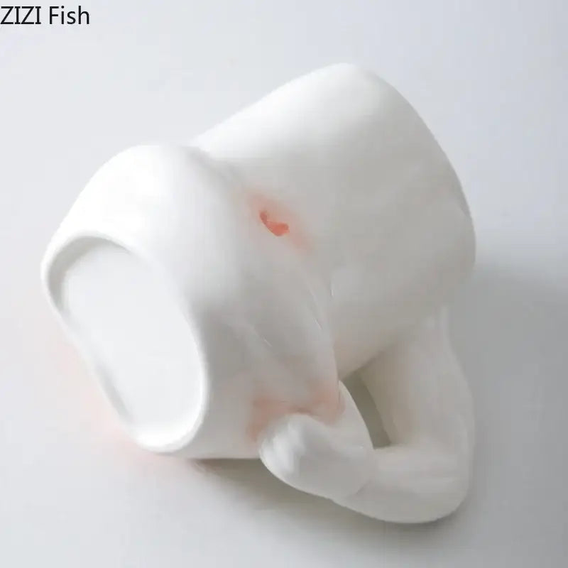 White ceramic creative pinch belly mug shaped like a sleeping creature with hand handle and subtle pink blush decorbites creative pinch