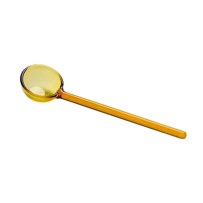 A translucent amber glass spoon from a creative purple and green glass spoon dessert set for ice cream and coffee