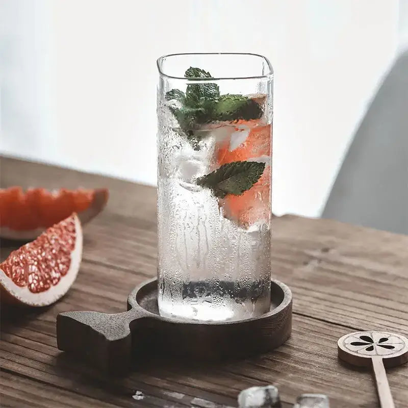 A clear creative square glass gold rim cold drink cup filled with ice citrus drink and fresh mint garnish