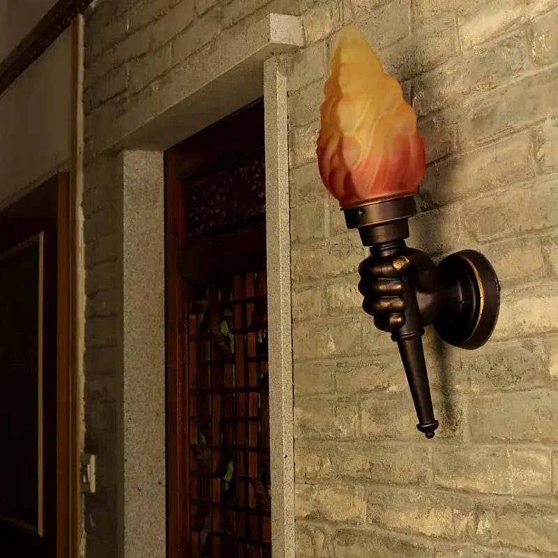 Creative torch hand wall lamp with bronze hand base and amber glass shade for living room decorbites creative torch