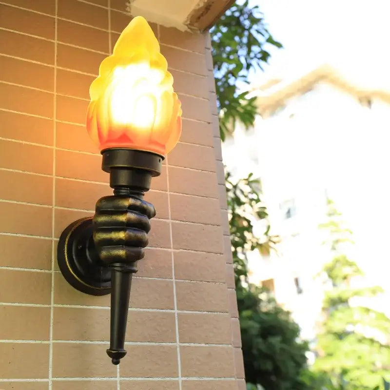 Creative torch hand wall lamp with warm bronze glass flame held by black metal hand for living room decorbites decor