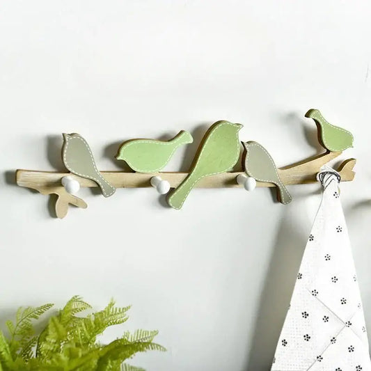 A wooden birds coat rack shaped like a branch with five painted birds in soft green and beige for entryway decor