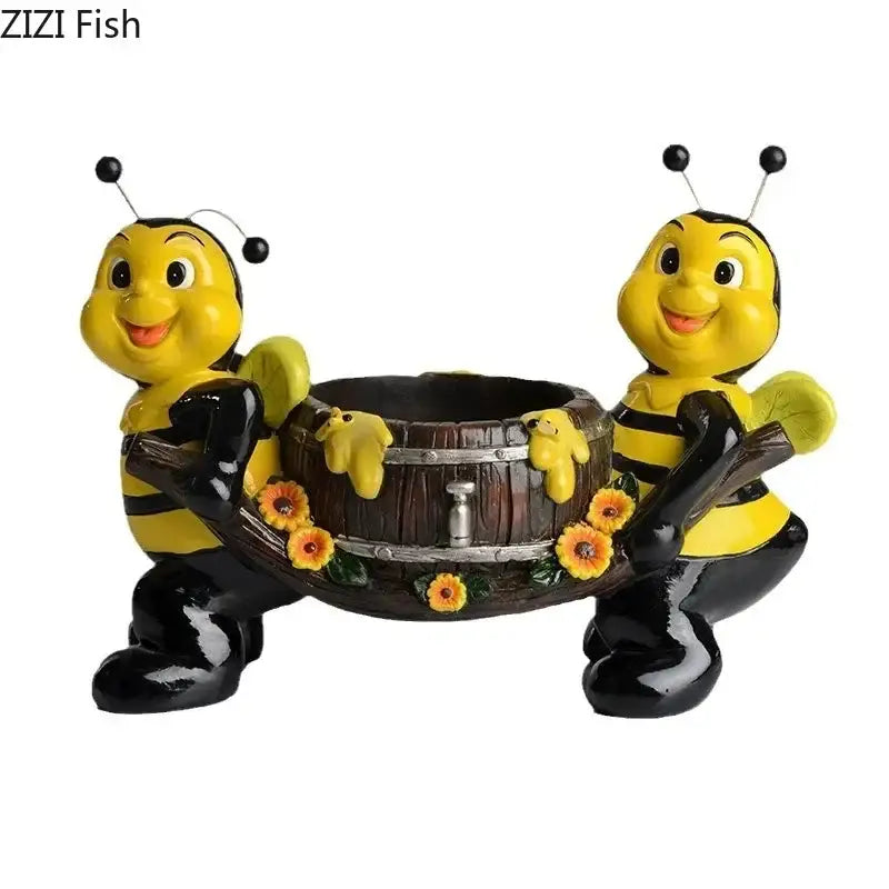 Two cheerful yellow and black bee resin vase characters holding a rustic wooden planter with orange flowers