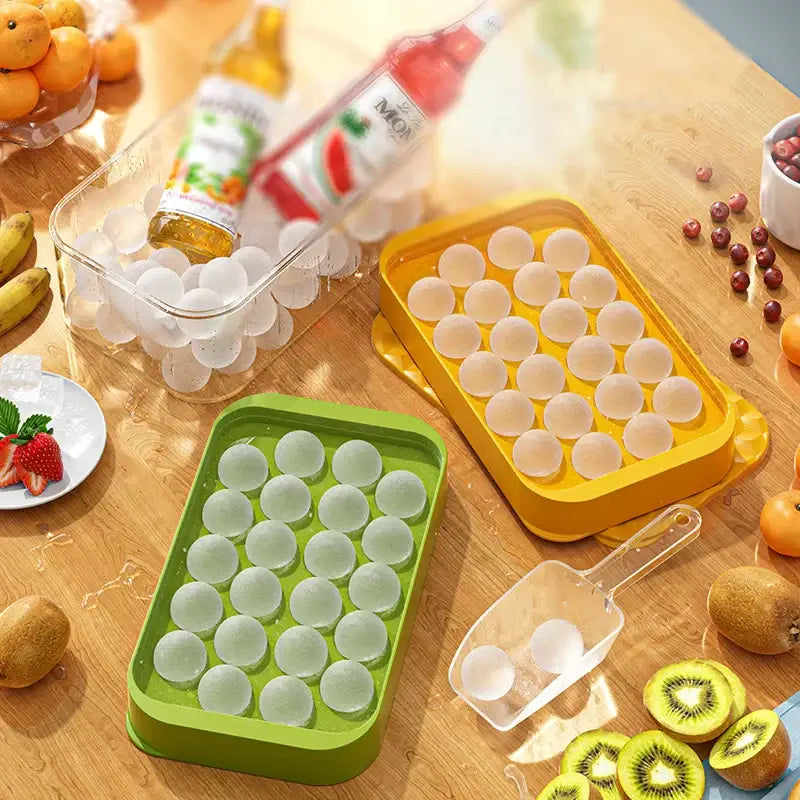 Set of green and yellow silicone ice mould trays with frozen spherical ice cubes for kitchen drink cooling