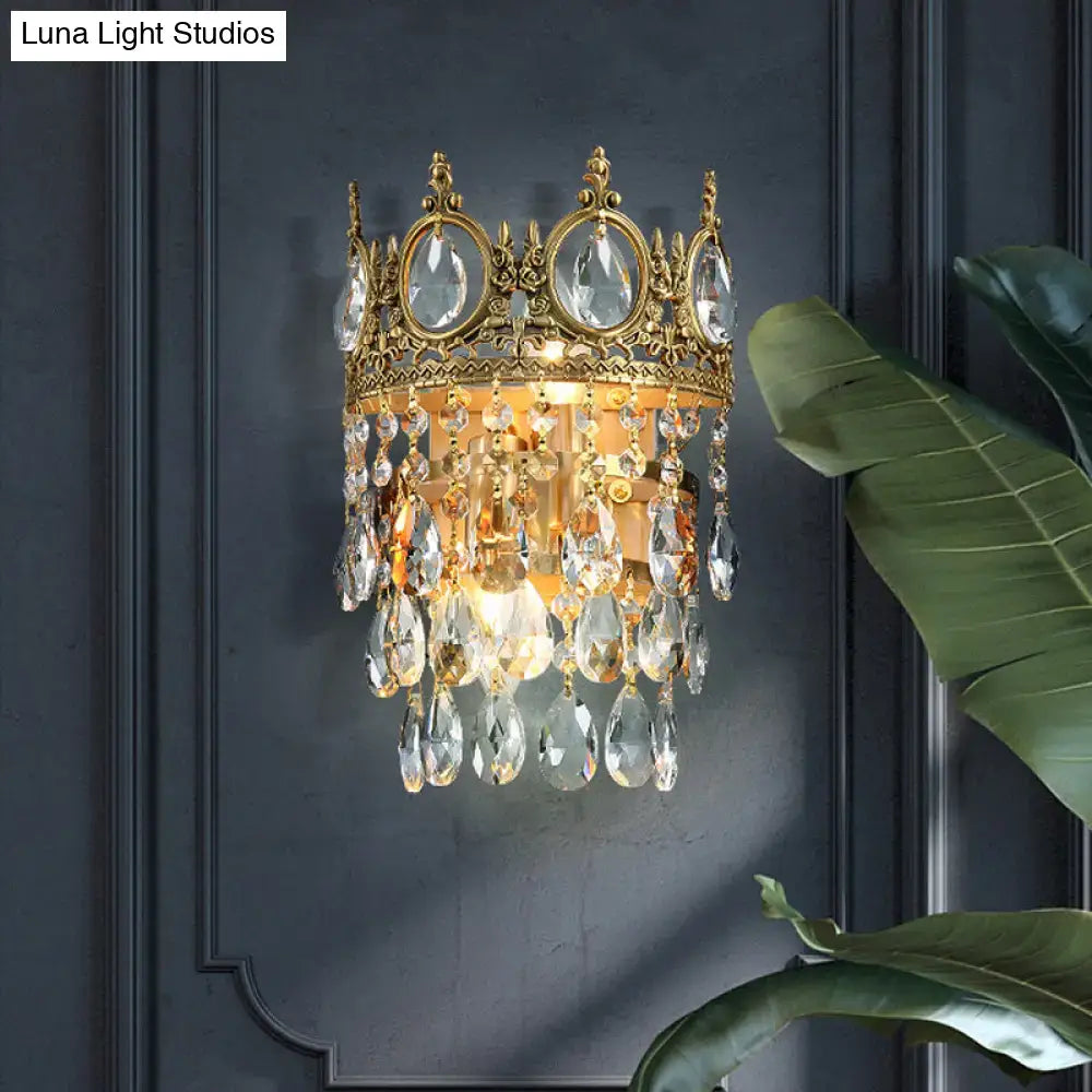 Gold-toned crown aged brass round wall mounted lighting with clear crystal prisms and dangling teardrop crystals