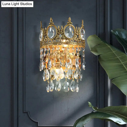 Gold-toned crown aged brass round wall mounted lighting with clear crystal prisms and dangling teardrop crystals