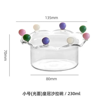 Clear glass fruit bowl with crown shaped rim adorned with colorful decorbites beads in pink green purple and cream