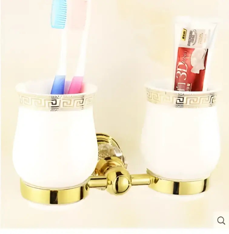 Gold-toned double toothbrush holder with white ceramic cups featuring greek key pattern in crystal bathroom accessories set