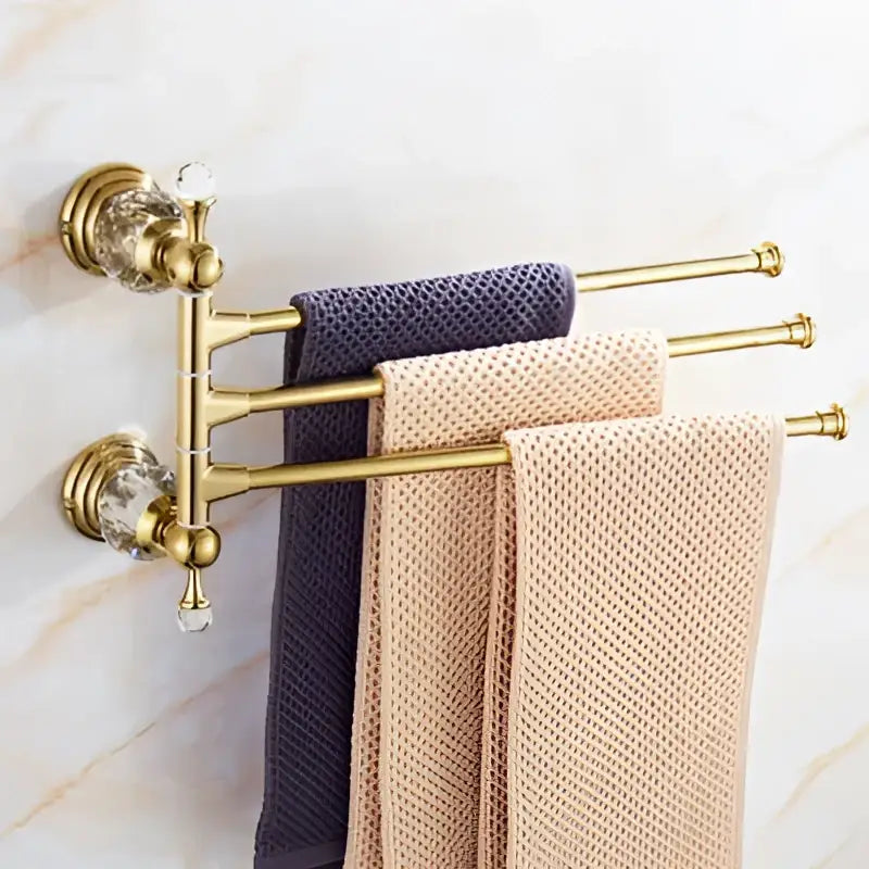 Gold-toned crystal bathroom accessories set with brass towel rack and navy beige textured towels by decorbites brass
