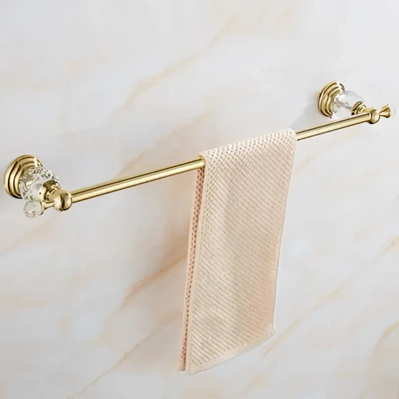 Gold-toned towel rack with crystal accents holding a light pink towel from crystal bathroom accessories set decorbites brass