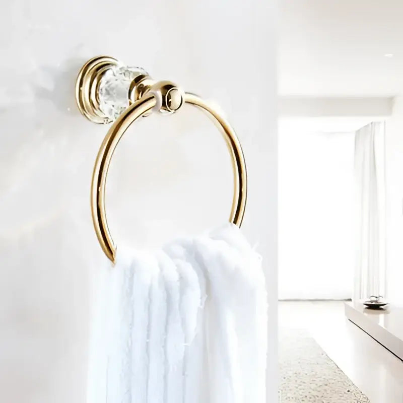 Gold-toned towel ring with clear crystal accent holding white towel from decorbites brass crystal bathroom accessories set